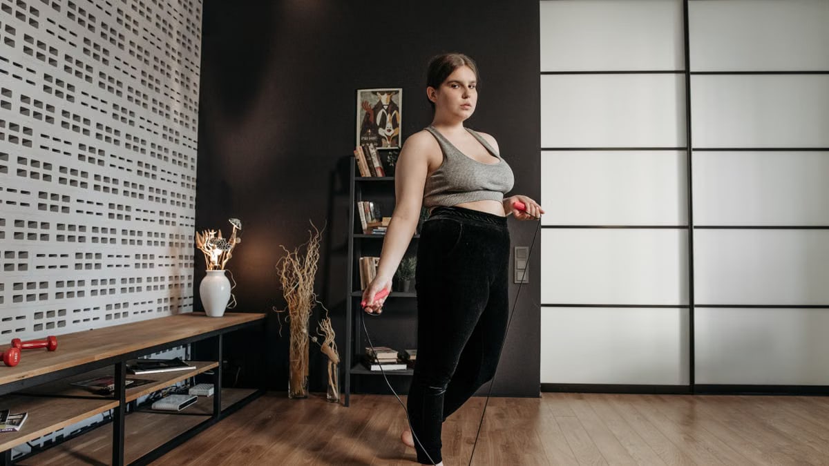 A woman performs a jump rope workout at home, focusing on fitness and health.